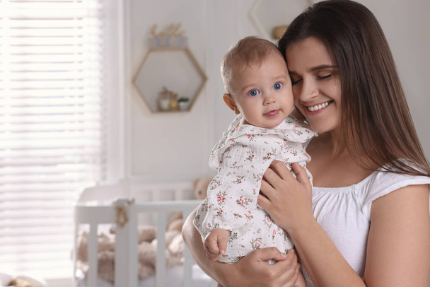 Happy young mother with her baby daughter in nursery. Space for text - Foto, Imagem