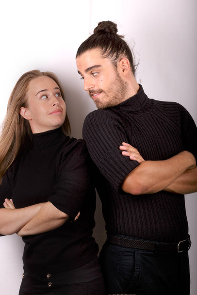 Молода і красива блондинка в чорному светрі і красивий чоловік в чорному светрі обидва роблять комічні жести на білому тлі
- - Фото, зображення