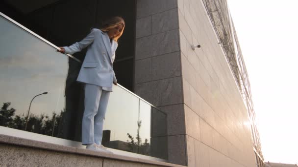 Sad upset stress woman in stylish blue suit business woman girl alone female standing at height on top high holding railing of terrace balcony looking down danger of falling suicide problem concept - Footage, Video