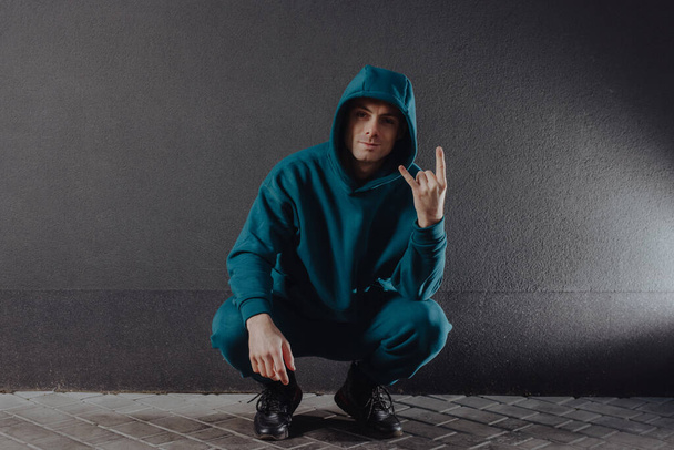 Cool man sitting in hood shows lets rock gesture - Foto, immagini