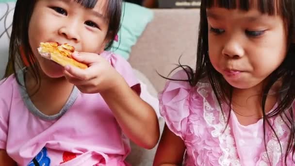 Aranyos testvér lányok pizzát esznek. Éhes gyerekek pizzát esznek otthon egy pizzapartin. Családi nyaralás fogalma. - Felvétel, videó