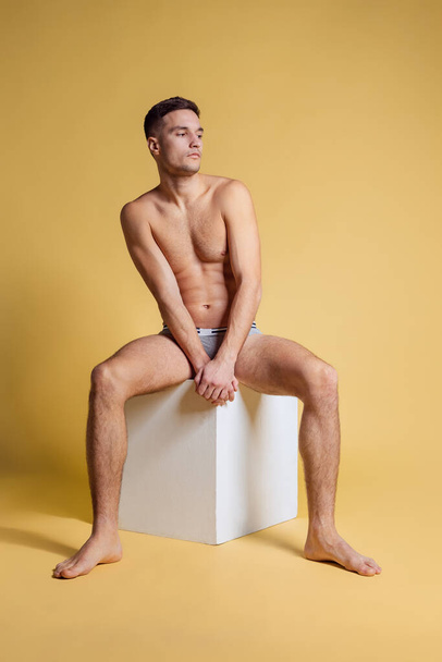 Studio shot of young handsome shirtless man isolated on yellow studio background. Natural beauty concept - Fotoğraf, Görsel