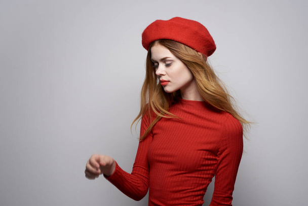 Başında kırmızı şapkalı güzel bir kadın stüdyoda poz veriyor. - Fotoğraf, Görsel