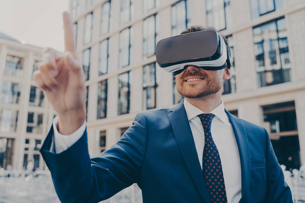 Επιχειρηματίας με επίσημο μπλε κοστούμι χρησιμοποιώντας γυαλιά VR έξω - Φωτογραφία, εικόνα