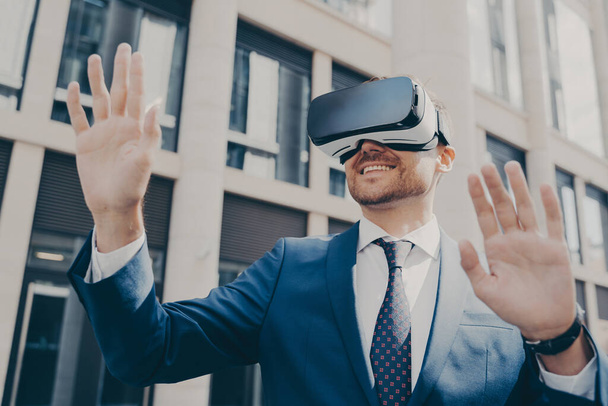 Profi beeindruckt Arbeiter, der allein draußen steht und mit VR-Brille Projekte visualisiert - Foto, Bild