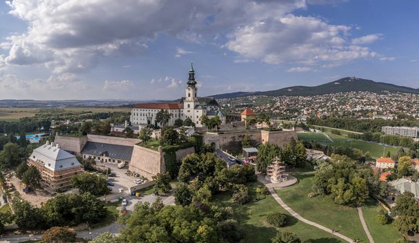 Luftaufnahme der Burg von Nitra. Kernstück der Burg ist die Kathedrale St. Emmeram mit Bischofssitz; der älteste erhaltene Teil ist die romanische Kirche, mittelalterliche Bastionen mit wolkenverhangenem Himmel - Foto, Bild