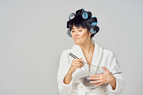 Donna vestita di bianco con bigodini in testa che fa i compiti in cucina - Foto, immagini