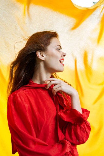 smiling woman in red dress posing yellow background - Foto, Bild