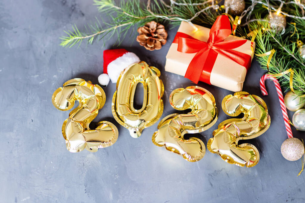 Happy new year 2022 background. Metallic balloons golden color on gray concrete background Flat lay, top view, mockup, overhead. Winter holiday celebration - Foto, Bild