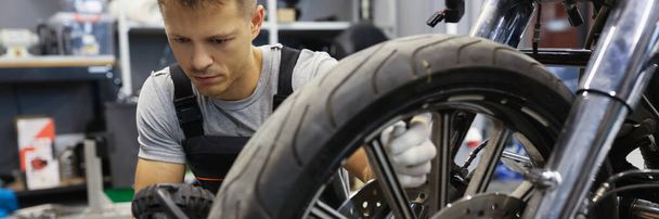 Homem verifica a pressão do pneu na motocicleta na oficina - Foto, Imagem