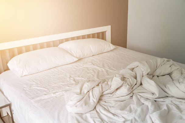 Két fehér párna az ágyon ráncos piszkos takaró a hálószobában háttér - Fotó, kép