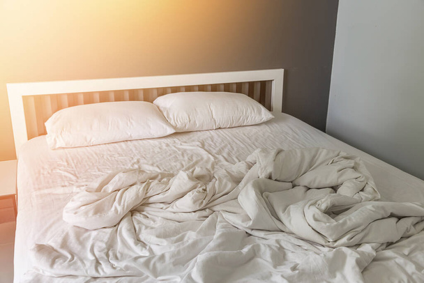 Twee witte kussen op bed met rimpel rommelige deken in slaapkamer achtergrond - Foto, afbeelding