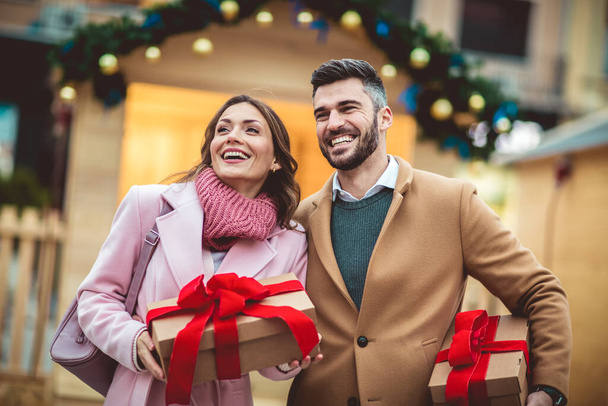 Young romantic couple holding gift box having fun outdoors in winter before Christmas. - Fotoğraf, Görsel