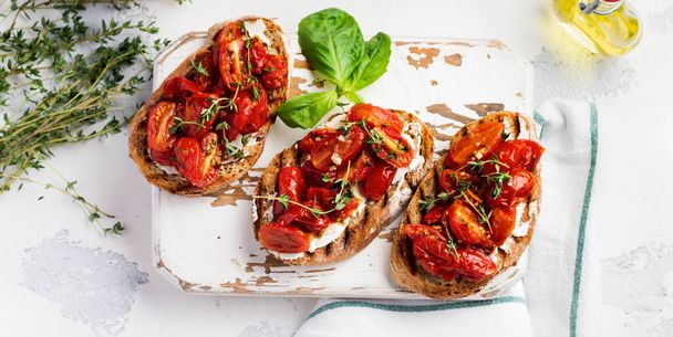 Sandwiches with baked cherry tomatoes and cottage cheese, thyme, garlic and herbs on an old light vintage background. Top view. - Fotoğraf, Görsel
