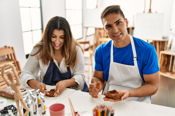Dos estudiantes sonriendo feliz modelado de arcilla sentado en la mesa en la escuela de arte. - Foto, imagen