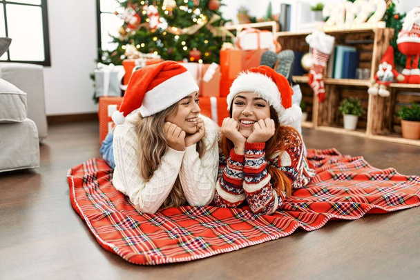 Vrouw paar glimlachen zelfverzekerd liggend op de vloer door kerst decor thuis - Foto, afbeelding
