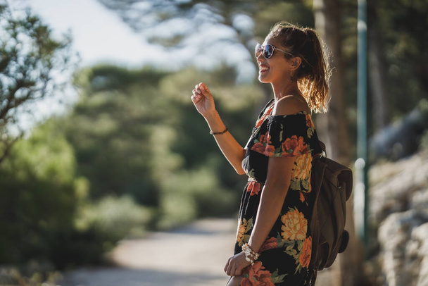 Усміхнена молода жінка насолоджується літнім відпочинком під час прогулянки сосновим лісом біля моря
. - Фото, зображення