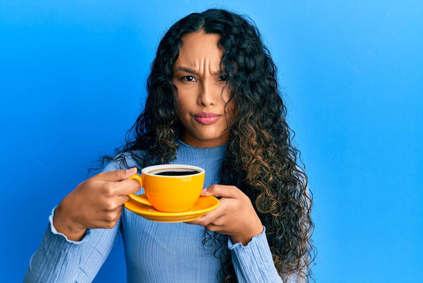 Молода латинка тримає каву скептично і нервово, розчаровуючись через проблеми. негативна людина
.  - Фото, зображення