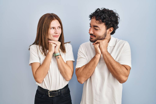 Young couple wearing casual clothes standing together laughing nervous and excited with hands on chin looking to the side  - Foto, afbeelding