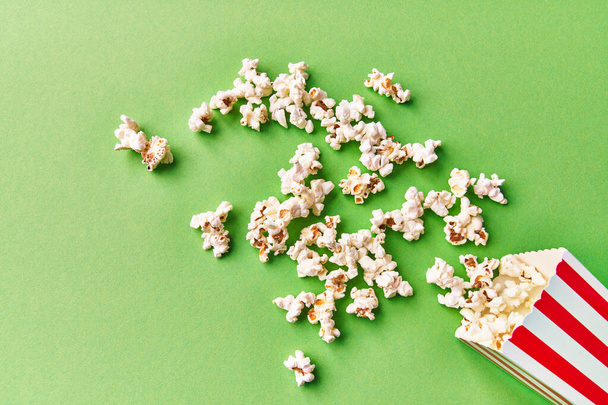  Pack of salty popcorns falling on a green background - Photo, Image