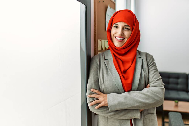 Young woman wearing arabic scarf standing with arms crossed gesture at office - Zdjęcie, obraz