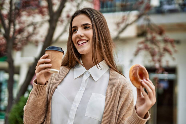 Junge hispanische Geschäftsfrau lächelt glücklich beim Frühstück in der Stadt. - Foto, Bild