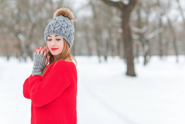 Kırmızı ceketli güzel bir genç kız. Kışlık Noel kıyafetleri ve arka planda yün bir şapka. Şık bir bayanın güneşli portresi. - Fotoğraf, Görsel