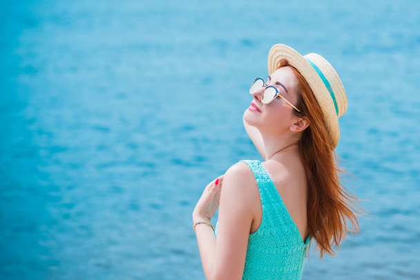 El tipo a la moda y romántico femenino. Chica en sombrero de paja en la playa en vestido turquesa - Foto, Imagen