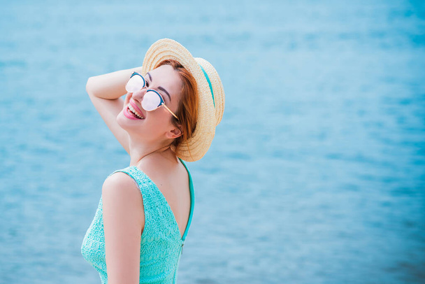 Модный и романтичный женский взгляд. Девушка в соломенной шляпе на пляже в бирюзовом платье - Фото, изображение