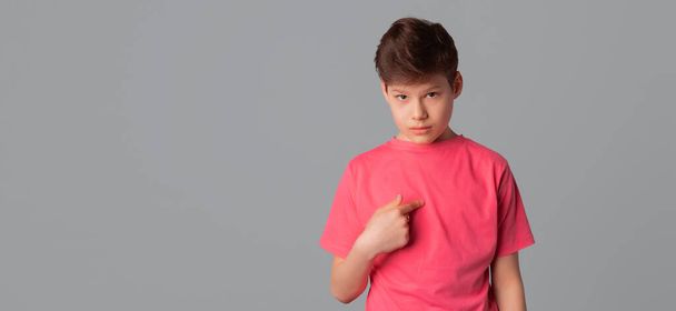 Kdo já. Mluvíš o mně. Pohledný teenager chlapec ukazuje prstem na sebe, oblečený v ležérní růžové tričko, stojící nad šedým pozadím s kopií volného místa pro text - Fotografie, Obrázek