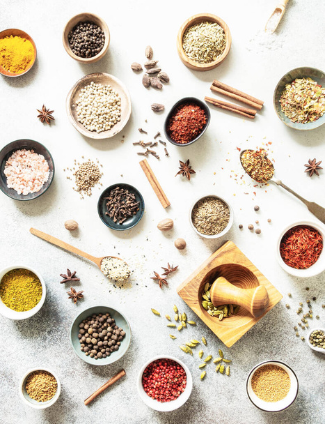 Various dry spices in small bowls and spoons flat lay on grey background. Top view - Foto, immagini
