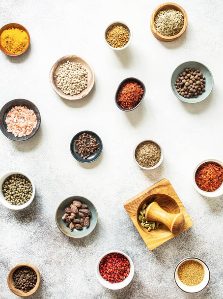 Various dry spices in small bowls and mortar flat lay on grey background. top view - Fotó, kép