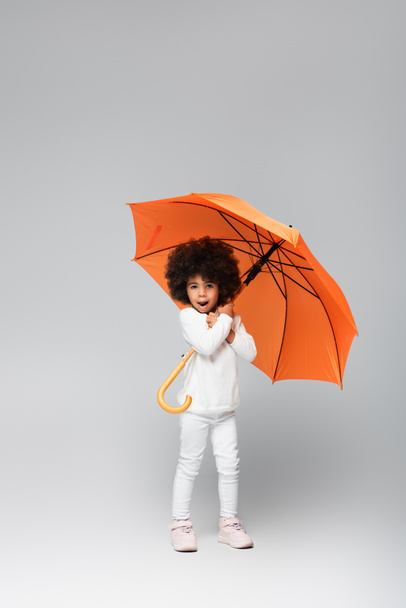 teljes hosszúságú kilátás afro-amerikai lány narancssárga esernyő álló fehér ruhák szürke - Fotó, kép