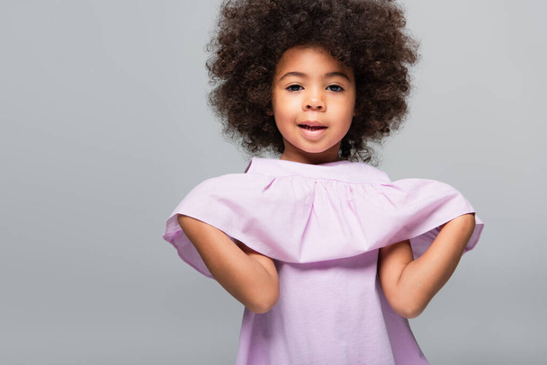 curly african american girl in violet blouse looking at camera isolated on grey - Fotoğraf, Görsel