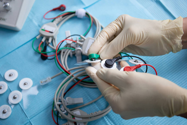 Γάντια χέρια γιατρού συνδέουν ηλεκτρόδια για συσκευή νευρομυϊκής διέγερσης - Φωτογραφία, εικόνα