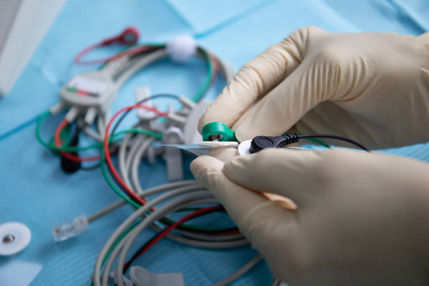 Руки врача в перчатках соединяют электроды для аппарата нервной стимуляции - Фото, изображение