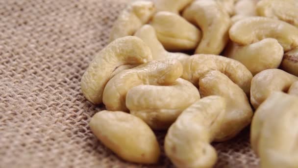 Cashew nut kernels on a rustic rough burlap. Raw organic seeds. Macro. Rotation - Кадры, видео