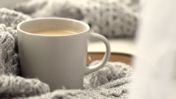 gemütliches Zuhause mit einer Tasse Kaffee und einem Buch. Hygge-Stil. Becher schwarzen Kaffees in warmen Schal auf Holzbrett gewickelt. Draufsicht, Vintage-Stil, Stillleben. - Filmmaterial, Video
