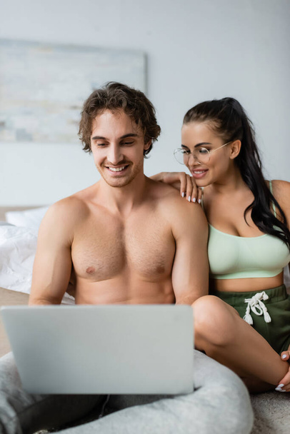 młoda sexy para za pomocą zamazanego laptopa w sypialni w domu  - Zdjęcie, obraz