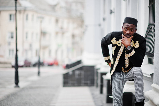 Mega stylish african man in traditional jacket pose. Fashionable black guy in hat. - Фото, зображення