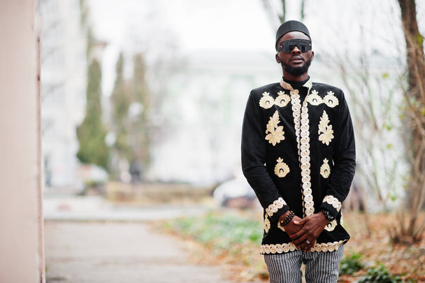 Mega stylish african man in traditional jacket pose. Fashionable black guy in hat and sunglasses. - Photo, image