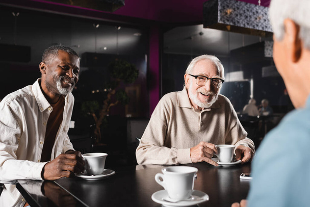 szczęśliwy wielonarodowy starszy przyjaciele pijąc kawę i rozmawiając w barze - Zdjęcie, obraz