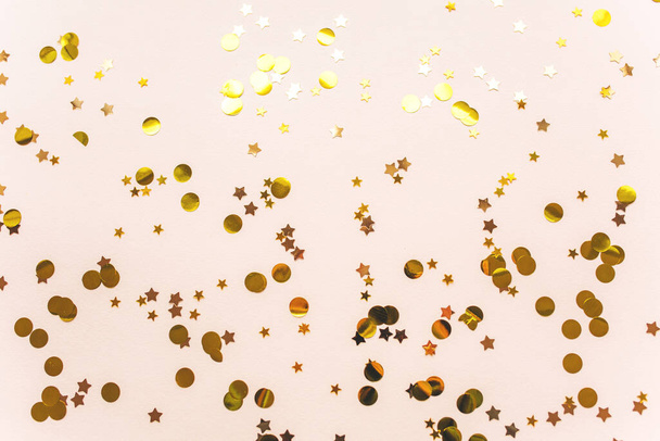 Gold Christmas ribbons and confetti on a pink background. Christmas or New Year conceptual background. - Foto, imagen