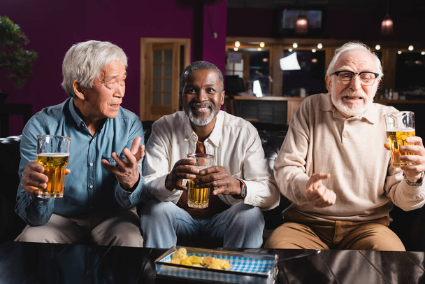 alegre africano americano hombre viendo fútbol partido con preocupado interracial amigos en deportes bar - Foto, imagen
