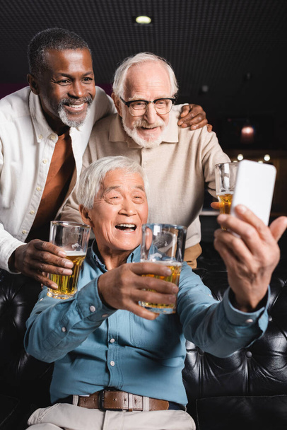 Mutlu Asyalı adam bira barında üst düzey çok kültürlü arkadaşlarıyla selfie çekiyor. - Fotoğraf, Görsel
