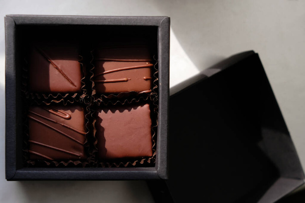 Chocolate gift set in a black box. Four pralines in brown paper cups. Craft chocolate in Ukraine. Natural sunlight. - Fotografie, Obrázek