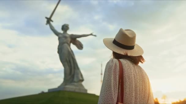 Una joven con un vestido mirando a la Madre Patria en el Mamayev Kurgan en Volgogrado - Imágenes, Vídeo