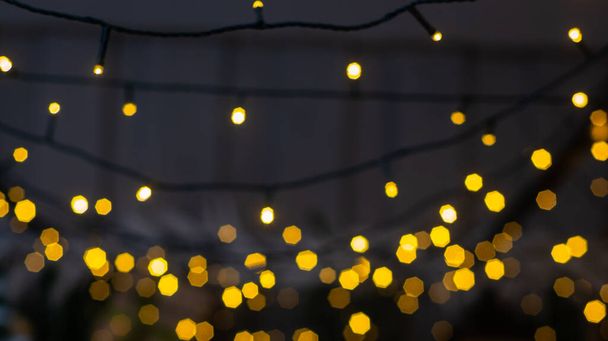 Unscharfe bunte Lichter einer Girlande und Äste eines Weihnachtsbaums im Vordergrund. Hintergrund Weihnachten und Neujahr. Selektiver Fokus, Kopierraum. - Foto, Bild