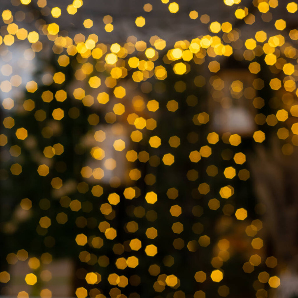 Zamazane wielobarwne światła girlandy i gałęzi choinki na pierwszym planie. Boże Narodzenie i Nowy Rok tła.Selektywne skupienie, przestrzeń kopiowania. - Zdjęcie, obraz
