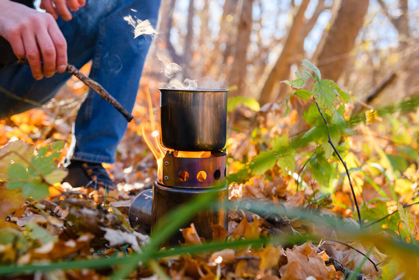 Металевий кухоль на відкритому вогні в лісі. Турист нагріває воду в металевому горщику на вогні в осінньому лісі
. - Фото, зображення